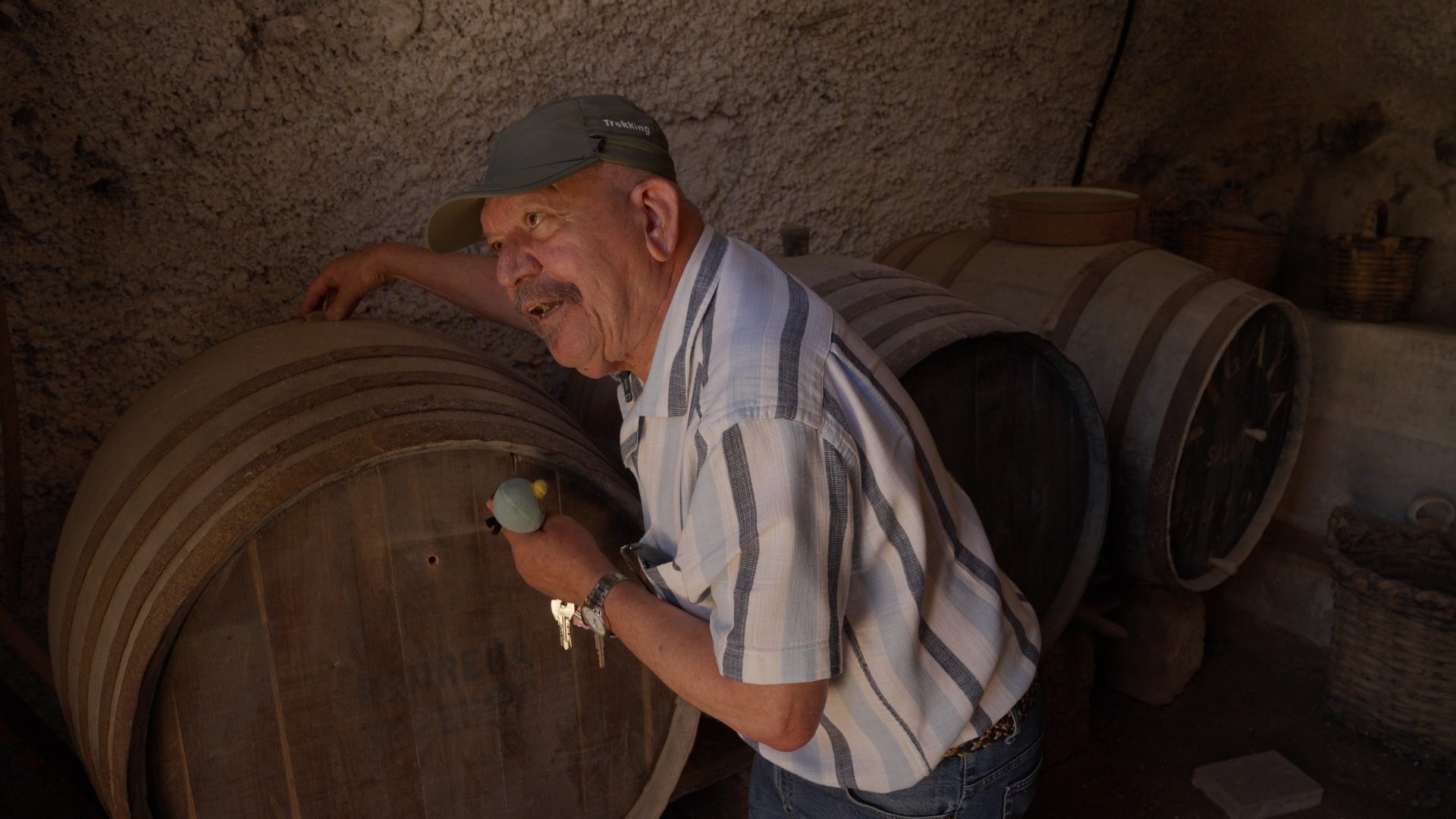 A man beside old wine barrels in the cellar